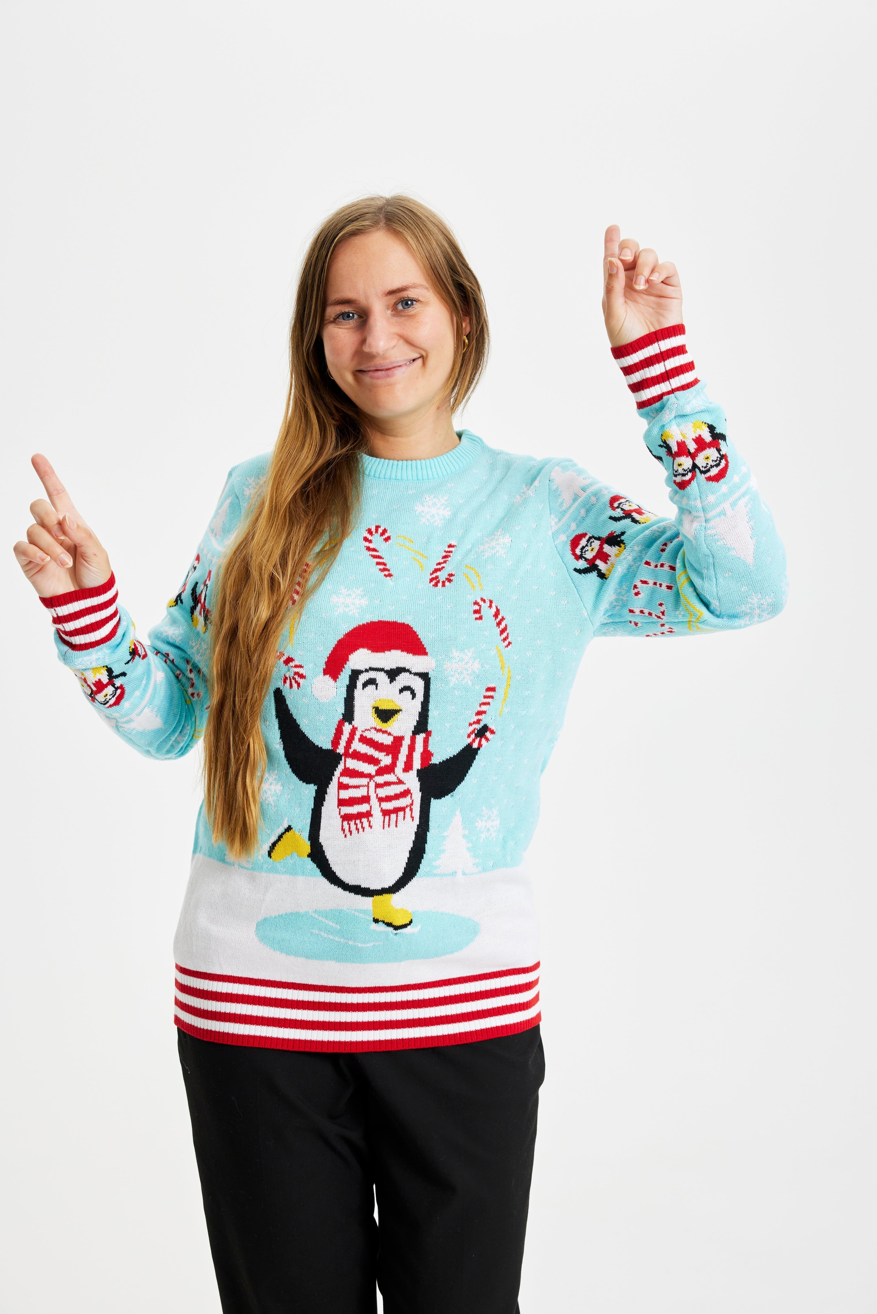 Een glimlachende vrouw die een lichtblauwe Kersttrui met pinguïns en lichten draagt.